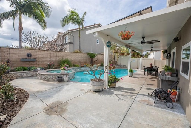 view of pool with a fenced backyard, ceiling fan, a patio area, a pool with connected hot tub, and outdoor dining space