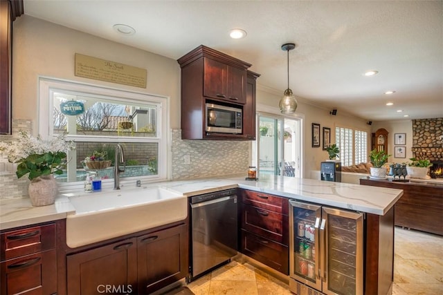 kitchen featuring a sink, stainless steel appliances, wine cooler, open floor plan, and a peninsula