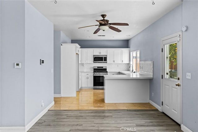 16129 Windcrest Dr, Fontana, CA 92337 - kitchen with appliances with stainless steel finishes, a peninsula, a ceiling fan, light wood-style floors, and decorative backsplash