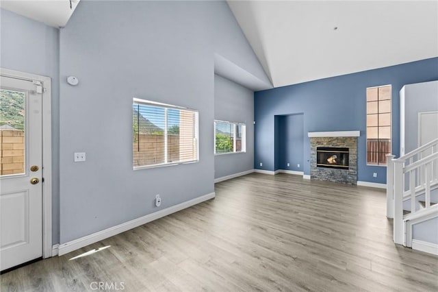 16129 Windcrest Dr, Fontana, CA 92337 - unfurnished living room featuring high vaulted ceiling, healthy amount of natural light, wood finished floors, a fireplace, and baseboards