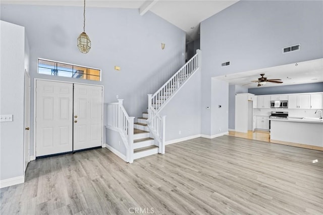 16129 Windcrest Dr, Fontana, CA 92337 - foyer entrance featuring high vaulted ceiling, stairway, beam ceiling, light wood finished floors, and baseboards
