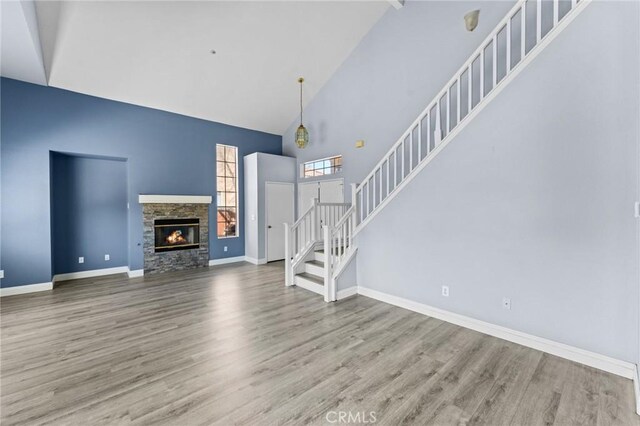 16129 Windcrest Dr, Fontana, CA 92337 - unfurnished living room with high vaulted ceiling, stairs, wood finished floors, baseboards, and a fireplace