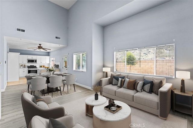 16129 Windcrest Dr, Fontana, CA 92337 - living area with baseboards, light wood-style flooring, a towering ceiling, and a ceiling fan