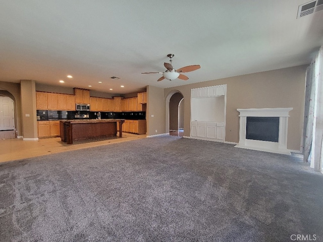 511 Milano Ct, Los Banos, CA 93635 - unfurnished living room featuring arched walkways, ceiling fan, light colored carpet, and recessed lighting