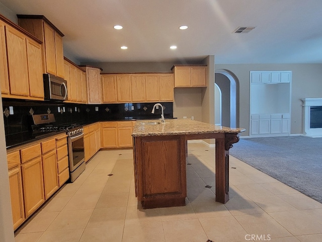 511 Milano Ct, Los Banos, CA 93635 - kitchen featuring stainless steel appliances, light colored carpet, recessed lighting, arched walkways, and tasteful backsplash