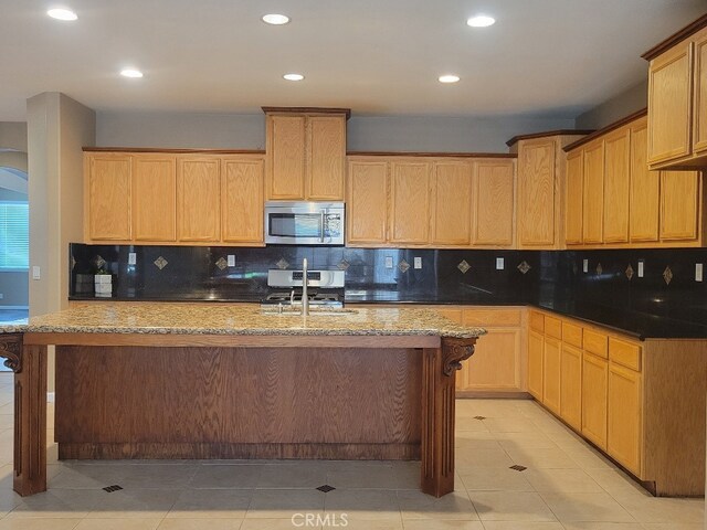 511 Milano Ct, Los Banos, CA 93635 - kitchen featuring stainless steel appliances, decorative backsplash, recessed lighting, a center island with sink, and a breakfast bar area