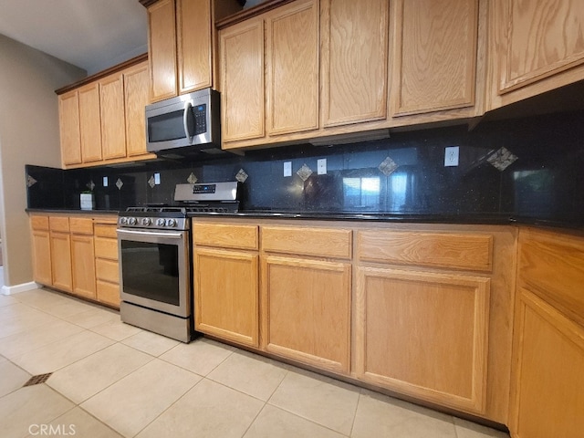 511 Milano Ct, Los Banos, CA 93635 - kitchen with stainless steel appliances, decorative backsplash, dark countertops, and light tile patterned floors
