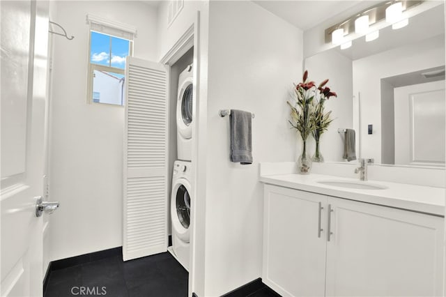 7 Abarrota St, Rancho Mission Viejo, CA 92694 - laundry area featuring stacked washer and clothes dryer, a sink, baseboards, and dark tile patterned flooring