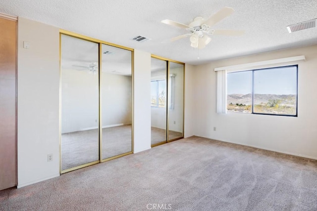 6425 Indian Cove Rd Unit 29, Palms, CA 92277 - unfurnished bedroom with carpet, two closets, a textured ceiling, and ceiling fan