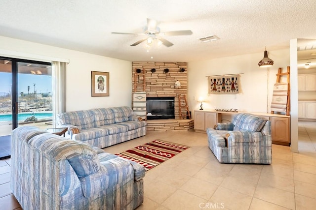 6425 Indian Cove Rd Unit 29, Palms, CA 92277 - living area featuring a ceiling fan, light tile patterned floors, a stone fireplace, and a textured ceiling