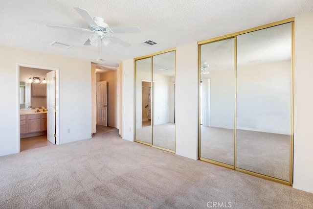 6425 Indian Cove Rd Unit 29, Palms, CA 92277 - unfurnished bedroom featuring carpet flooring, two closets, connected bathroom, a textured ceiling, and ceiling fan