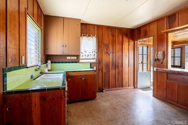 6425 Indian Cove Rd Unit 29, Palms, CA 92277 - kitchen featuring tile counters, a sink, wooden walls, light flooring, and brown cabinets