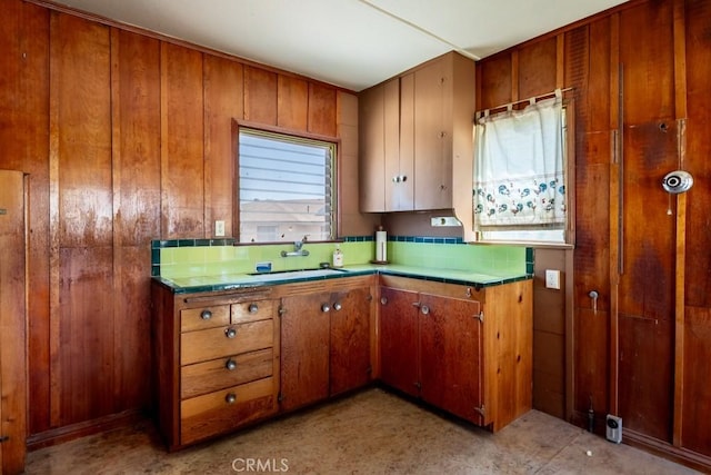 6425 Indian Cove Rd Unit 29, Palms, CA 92277 - kitchen featuring a sink, brown cabinets, tile counters, and wooden walls