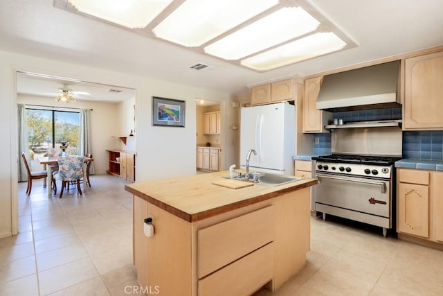 6425 Indian Cove Rd Unit 29, Palms, CA 92277 - kitchen with light brown cabinets, wall chimney range hood, a sink, freestanding refrigerator, and stainless steel range