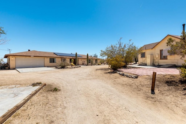 6425 Indian Cove Rd Unit 29, Palms, CA 92277 - single story home with roof mounted solar panels, an attached garage, stucco siding, and driveway