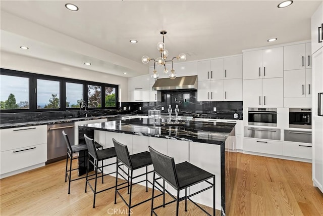 kitchen featuring extractor fan, a warming drawer, stainless steel appliances, tasteful backsplash, and recessed lighting