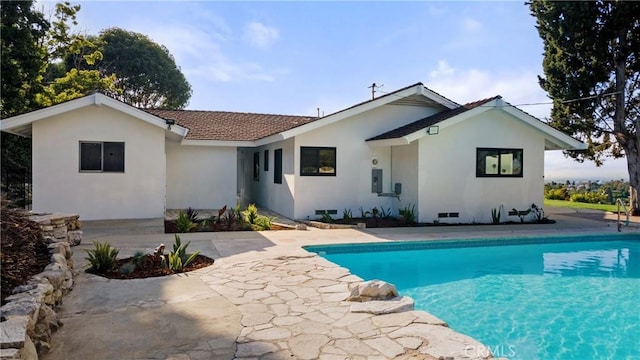 rear view of property with an outdoor pool, a patio area, and stucco siding