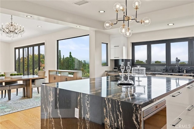 kitchen featuring a chandelier, a sink, recessed lighting, plenty of natural light, and light wood finished floors