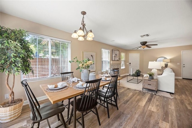 1534 Rowan Gln, Escondido, CA 92025 - dining room with wood finished floors, a ceiling fan, a lit fireplace, and a chandelier