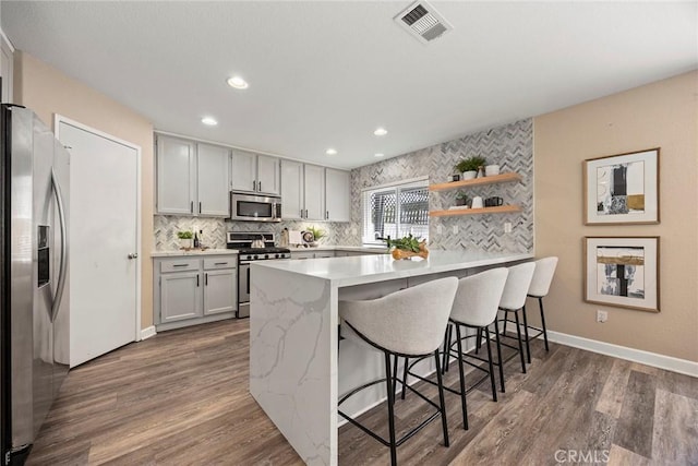 1534 Rowan Gln, Escondido, CA 92025 - kitchen featuring stainless steel appliances, a peninsula, a kitchen breakfast bar, wood finished floors, and recessed lighting