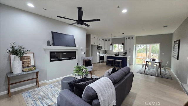 6485 Providence Ct, Magalia, CA 95954 - living room with a glass covered fireplace, baseboards, a ceiling fan, recessed lighting, and light wood finished floors