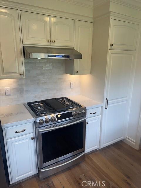 3108 Sumatra Pl, Costa Mesa, CA 92626 - kitchen with gas range, wall chimney exhaust hood, white cabinetry, and dark wood-style floors