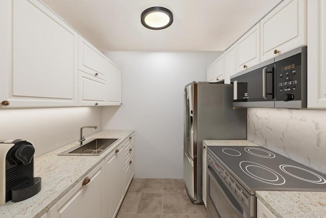 kitchen with stainless steel appliances, a sink, white cabinets, backsplash, and light tile patterned flooring