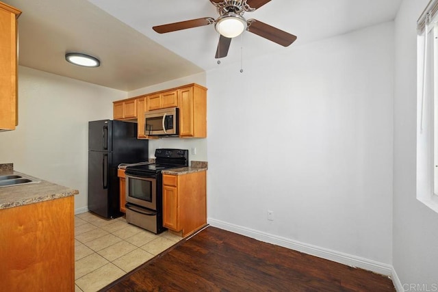 kitchen featuring stainless steel appliances, ceiling fan, baseboards, a sink, and light wood-style flooring