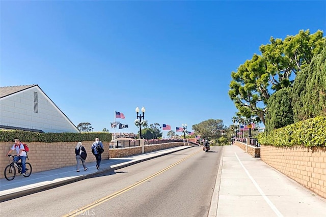 view of asphalt street with sidewalks, curbs, and street lighting
