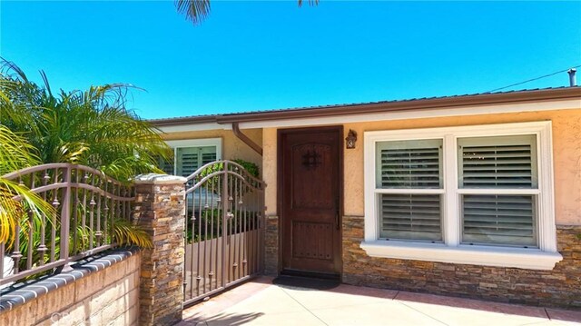 2018 Anaheim Ave, Costa Mesa, CA 92627 - entrance to property with a gate, stucco siding, metal roof, and stone siding