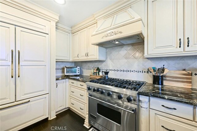 2018 Anaheim Ave, Costa Mesa, CA 92627 - kitchen with stainless steel stove, custom range hood, backsplash, dark stone counters, and dark wood finished floors