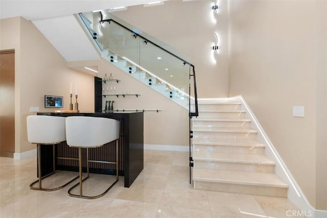 indoor wet bar featuring stairs, baseboards, and tile patterned flooring