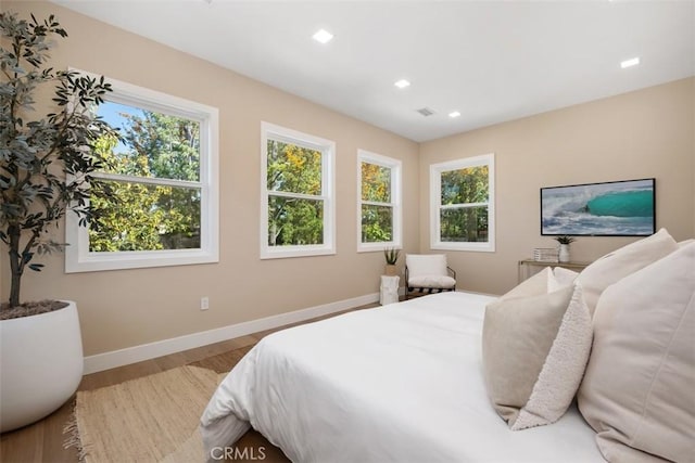 bedroom with baseboards, wood finished floors, and recessed lighting