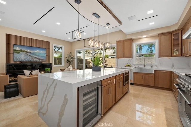 kitchen with beverage cooler, a sink, stainless steel range, brown cabinets, and recessed lighting