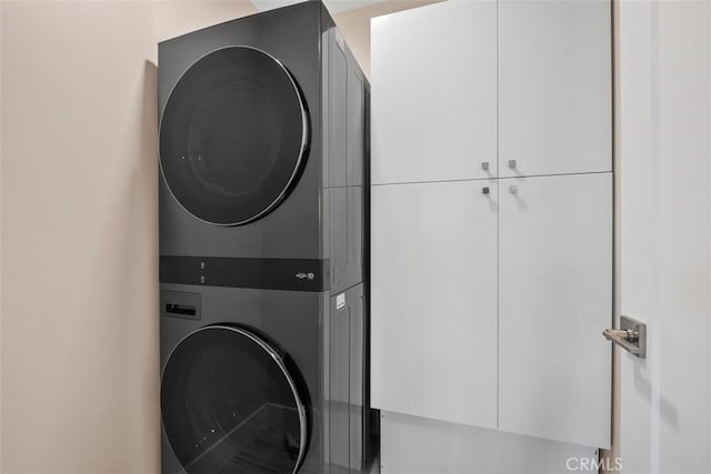 laundry area featuring estacked washer and dryer and cabinet space