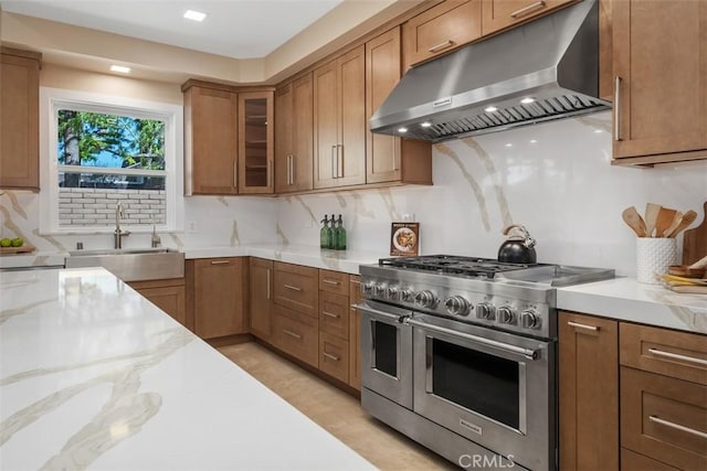 kitchen with range with two ovens, under cabinet range hood, a sink, and backsplash
