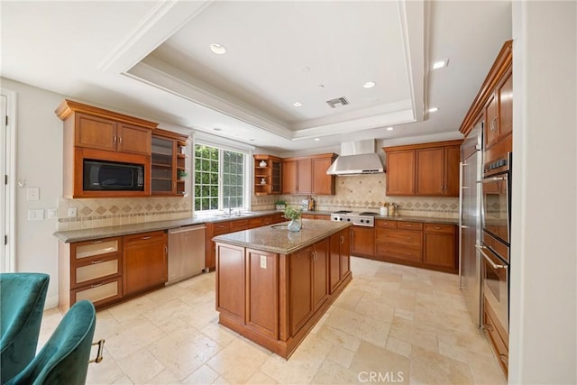 15850 Seville Ln, Encino, CA 91436 - kitchen featuring appliances with stainless steel finishes, wall chimney exhaust hood, a tray ceiling, brown cabinetry, and a sink