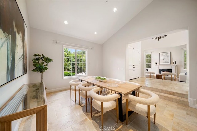 15850 Seville Ln, Encino, CA 91436 - dining room with stone tile floors, healthy amount of natural light, recessed lighting, a warm lit fireplace, and baseboards