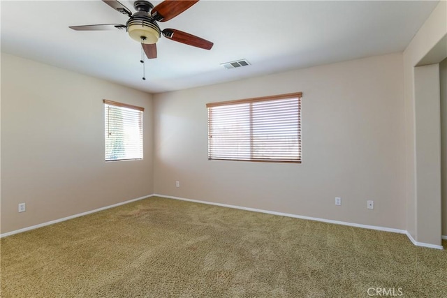 carpeted spare room featuring baseboards and a ceiling fan