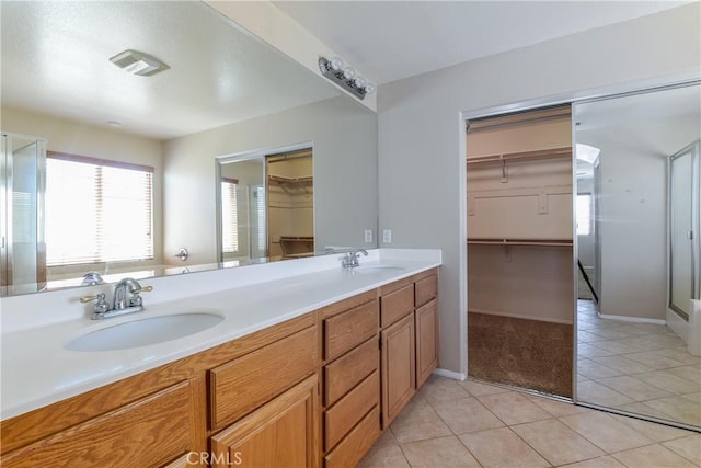 full bathroom featuring tile patterned flooring, a walk in closet, double vanity, and baseboards