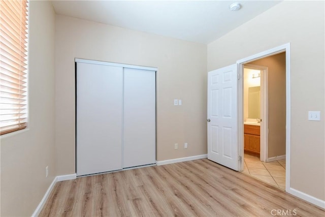 unfurnished bedroom featuring light wood-style floors, a closet, and baseboards