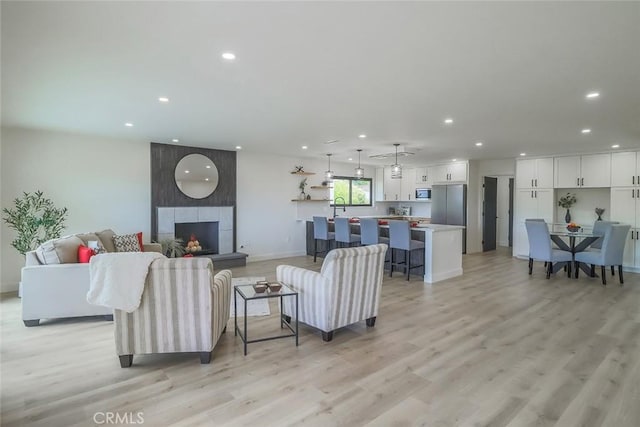 living room with recessed lighting, light wood finished floors, baseboards, and a tiled fireplace