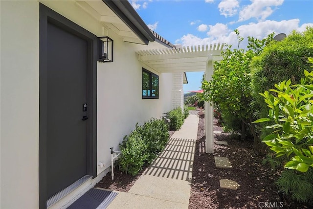 view of side of property featuring stucco siding and a pergola