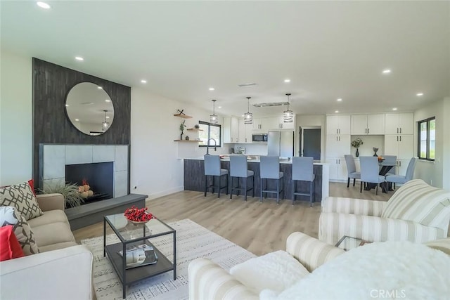 living room featuring light wood-style flooring, recessed lighting, baseboards, and a fireplace