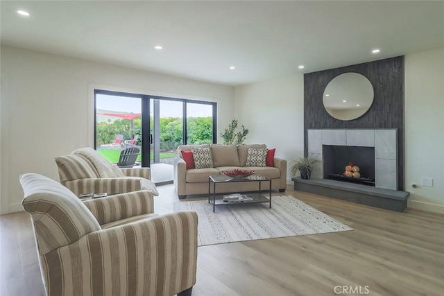 living room with recessed lighting, wood finished floors, a tiled fireplace, and baseboards