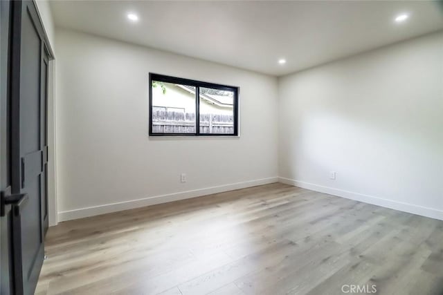 unfurnished room with recessed lighting, light wood finished floors, and baseboards