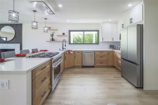 kitchen featuring stainless steel appliances, a sink, light wood finished floors, light countertops, and pendant lighting