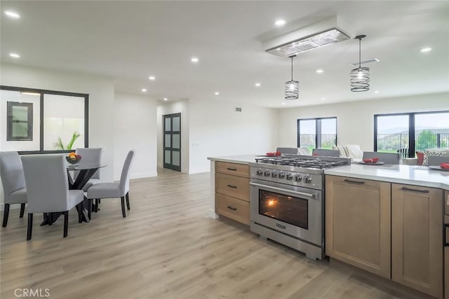 kitchen featuring high end stainless steel range, light wood-style floors, recessed lighting, light countertops, and decorative light fixtures