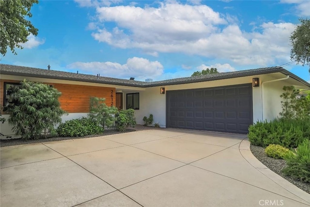 ranch-style home featuring stucco siding, a garage, and concrete driveway