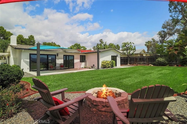rear view of property with stucco siding, a fire pit, and a patio